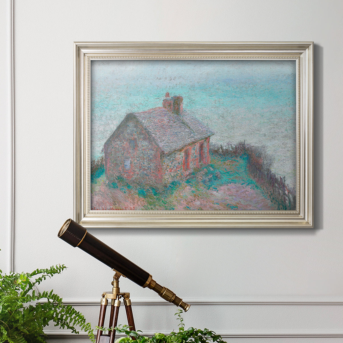 Impressionist coastal building landscape by Claude Monet in an ornate champagne frame displayed in a light-toned interior setting.