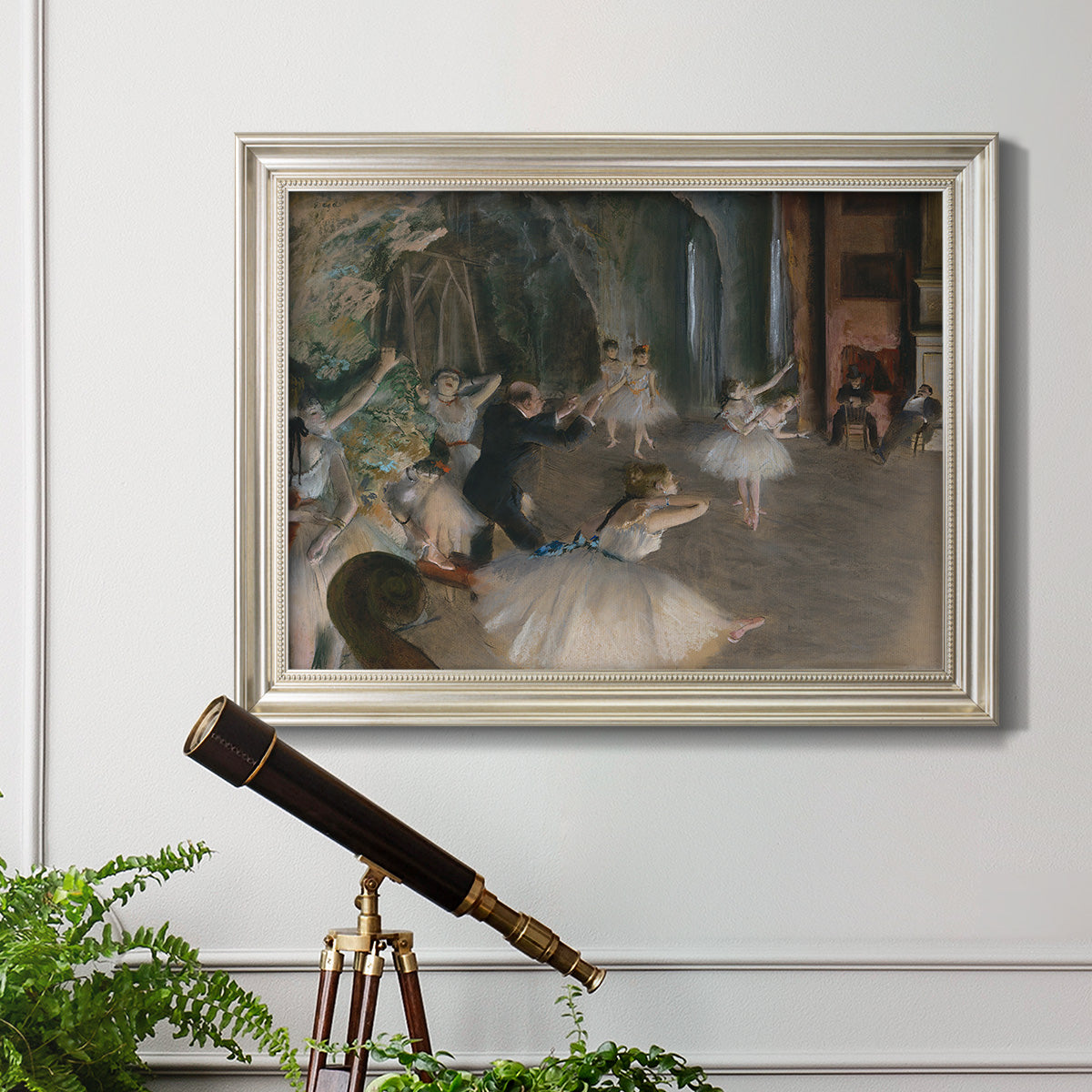 Impressionist backstage ballet scene by Edgar Degas in an ornate champagne frame displayed in a light-toned interior setting.