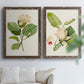 Set of two walnut barnwood framed canvas prints depicting large pale petals, leafy branches, and soft watercolor shading arranged across two complementary compositions above a sofa in a bright living space.