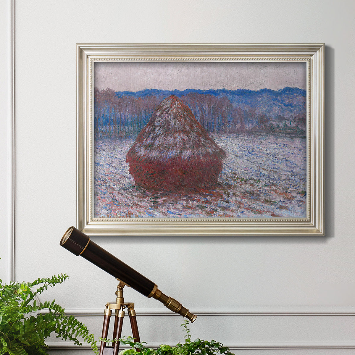 Impressionist single haystack landscape by Claude Monet in an ornate champagne frame displayed in a light-toned interior setting.