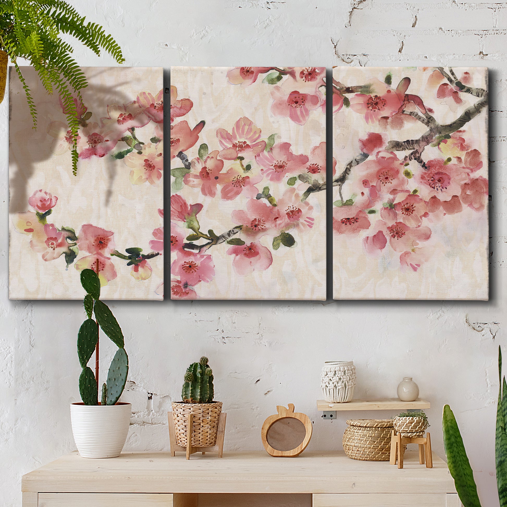 Three-panel canvas wall art featuring blooming cherry blossom branches, displayed in a boho-chic entryway above a console table.