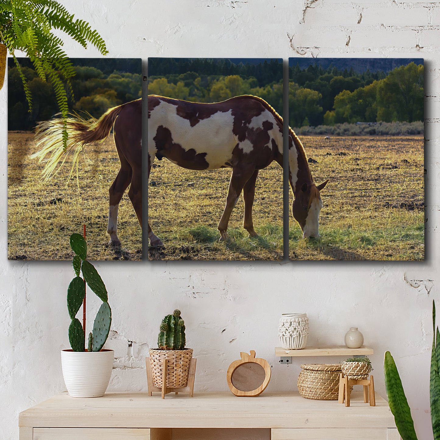 Three-panel canvas wall art featuring horses standing near farmhouse, displayed in a boho-chic entryway above a console table.