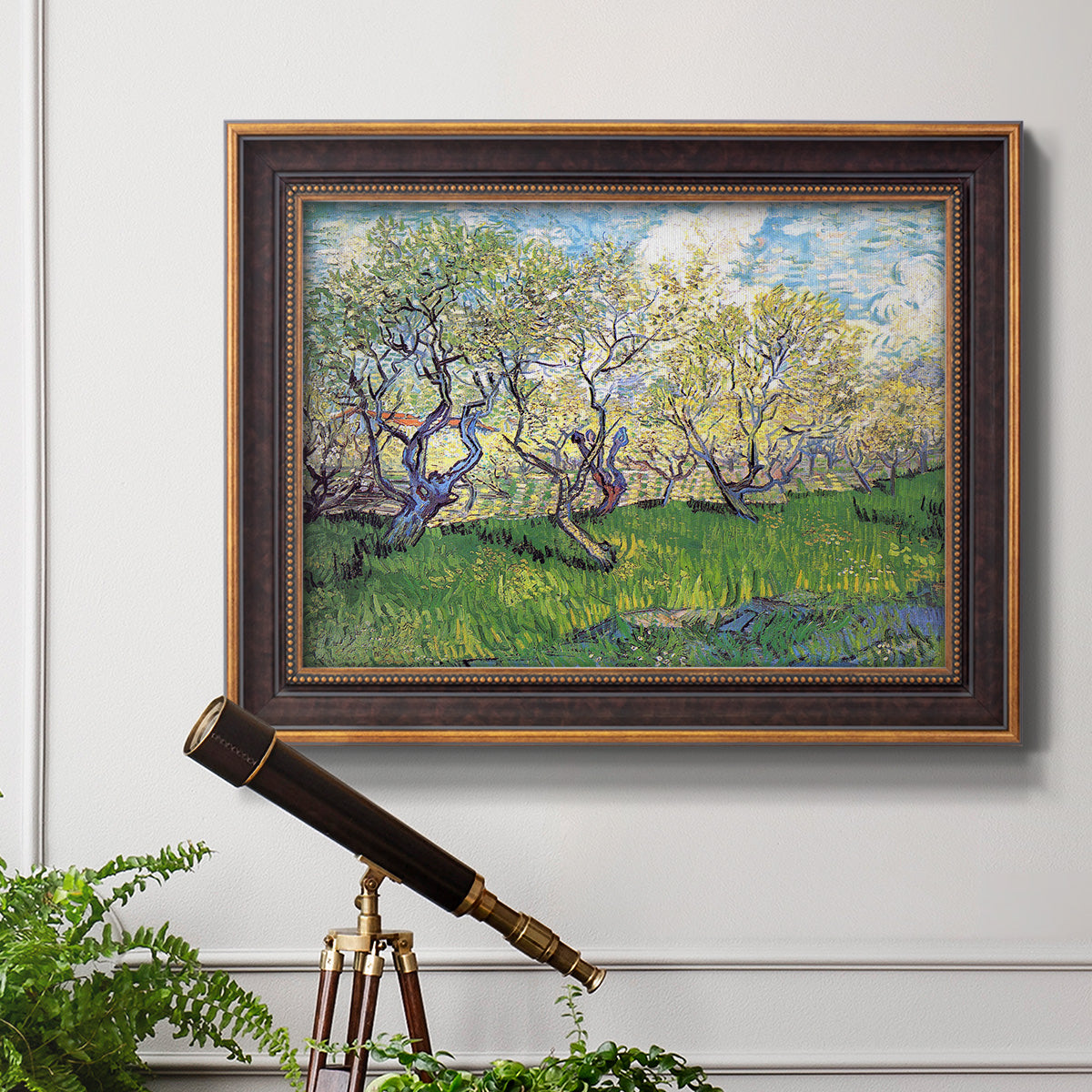 Impressionist spring orchard landscape by Vincent van Gogh in an ornate bronzed mahogany wood frame displayed in a light-toned interior setting.