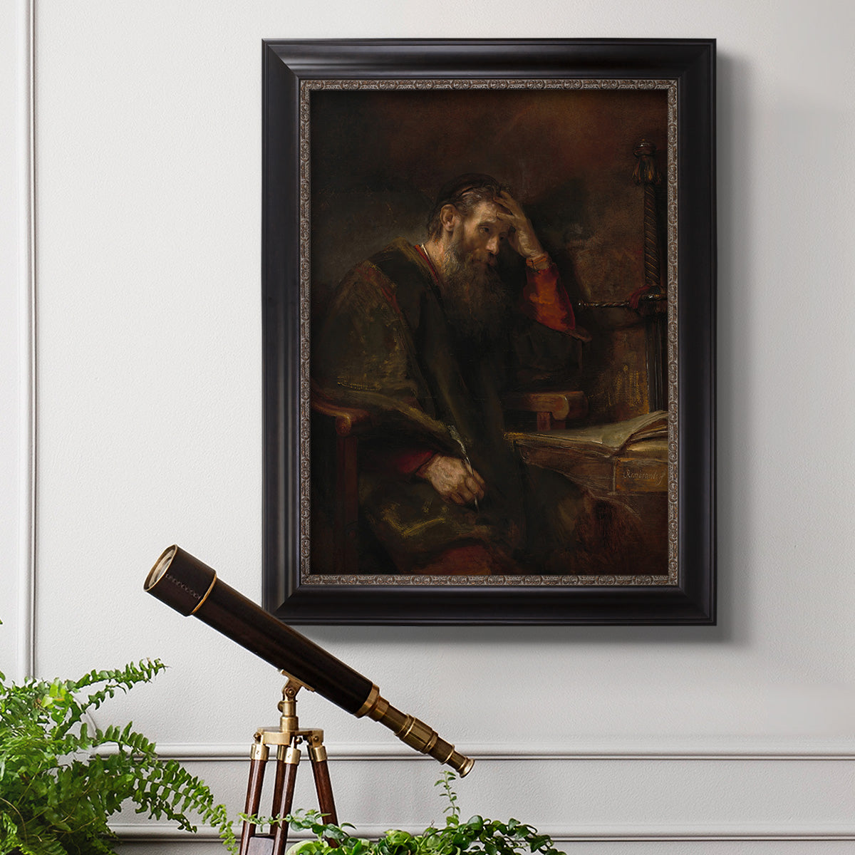 Classical religious portrait of Paul the Apostle by Rembrandt van Rijn in an ornate black frame with gilded inner detail displayed in a light-toned interior setting.