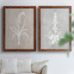 Set of two maple barnwood framed canvas prints depicting delicate stems, leaves, and blossoms against gray taupe and pale blue panels arranged across two complementary compositions above a sofa in a bright living space.
