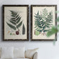 Set of two black barnwood framed canvas prints depicting varied green fronds, roots, spores, and archival labels arranged across two complementary compositions above a sofa in a bright living space.