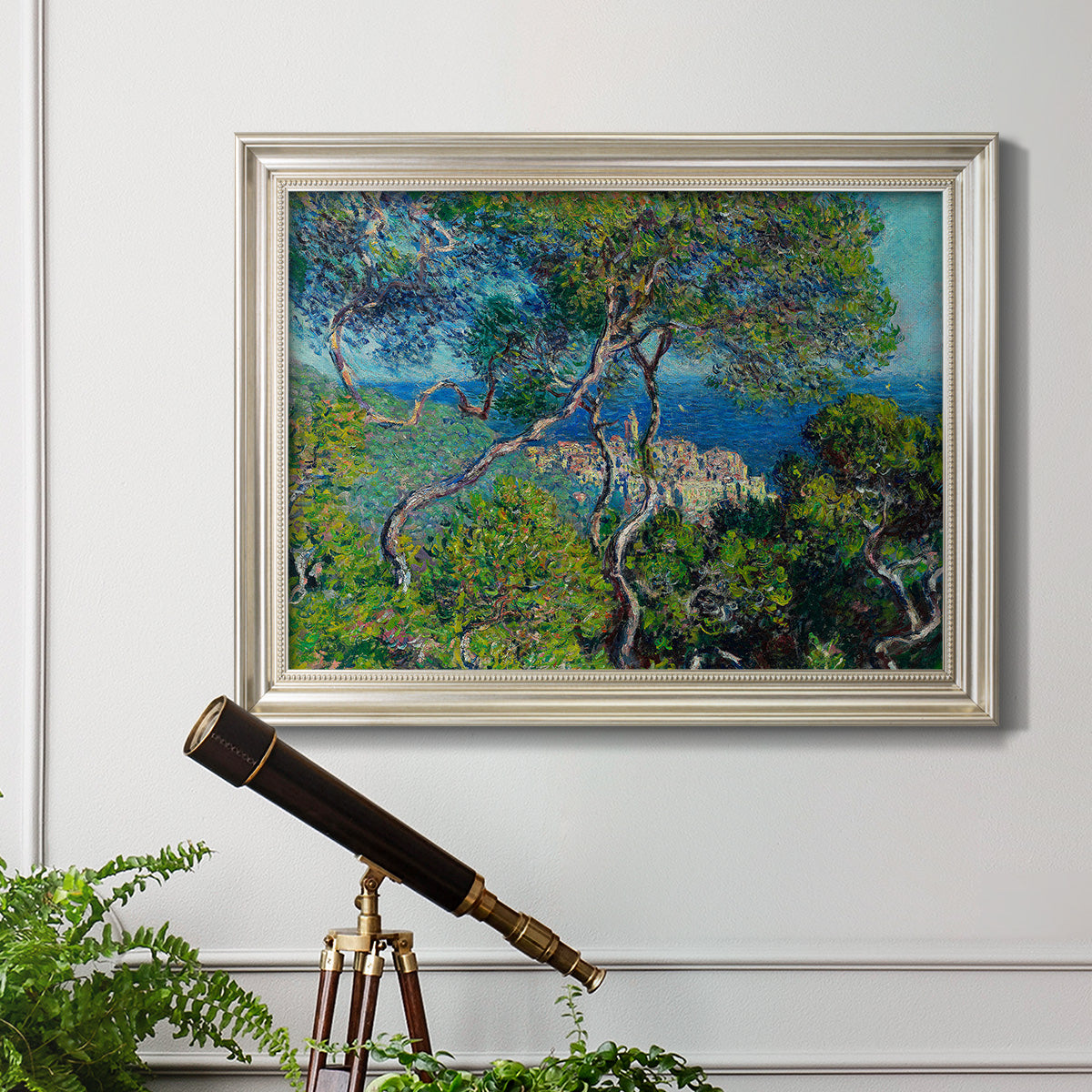 Impressionist Mediterranean coastal landscape by Claude Monet in an ornate champagne frame displayed in a light-toned interior setting.