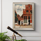 Realist city street scene by Johannes Vermeer in an ornate champagne frame displayed in a light-toned interior setting.