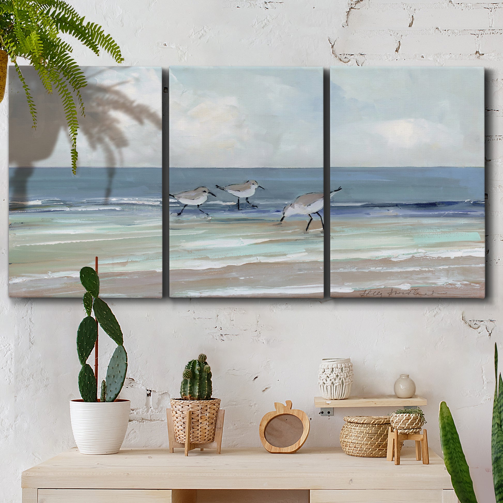 Three-panel canvas wall art featuring shore birds searching along beach, displayed in a boho-chic entryway above a console table.