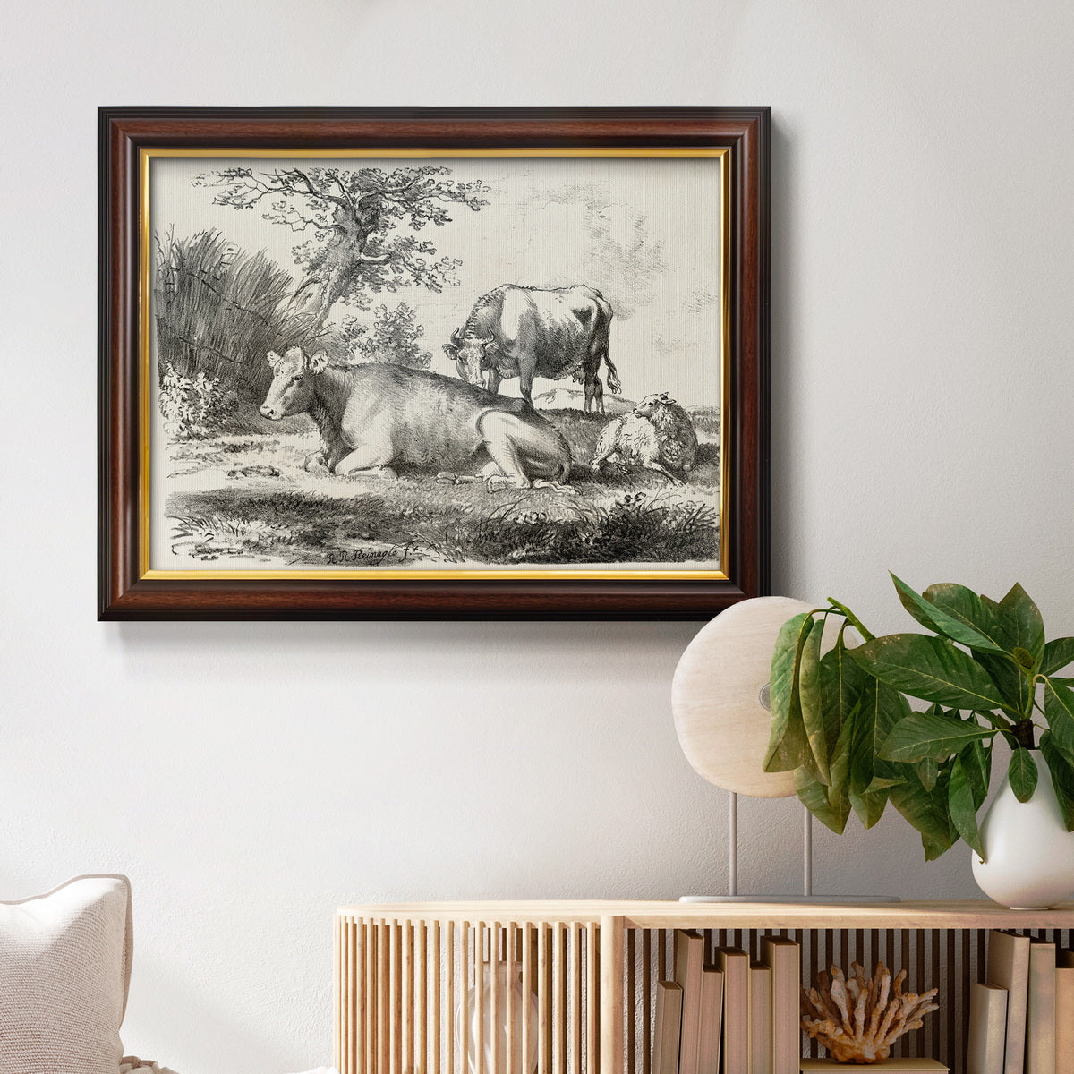 Classical pastoral landscape artwork by Nicolas Berchem in an ornate mahogany wood frame with gold liner displayed in a light-toned interior setting.