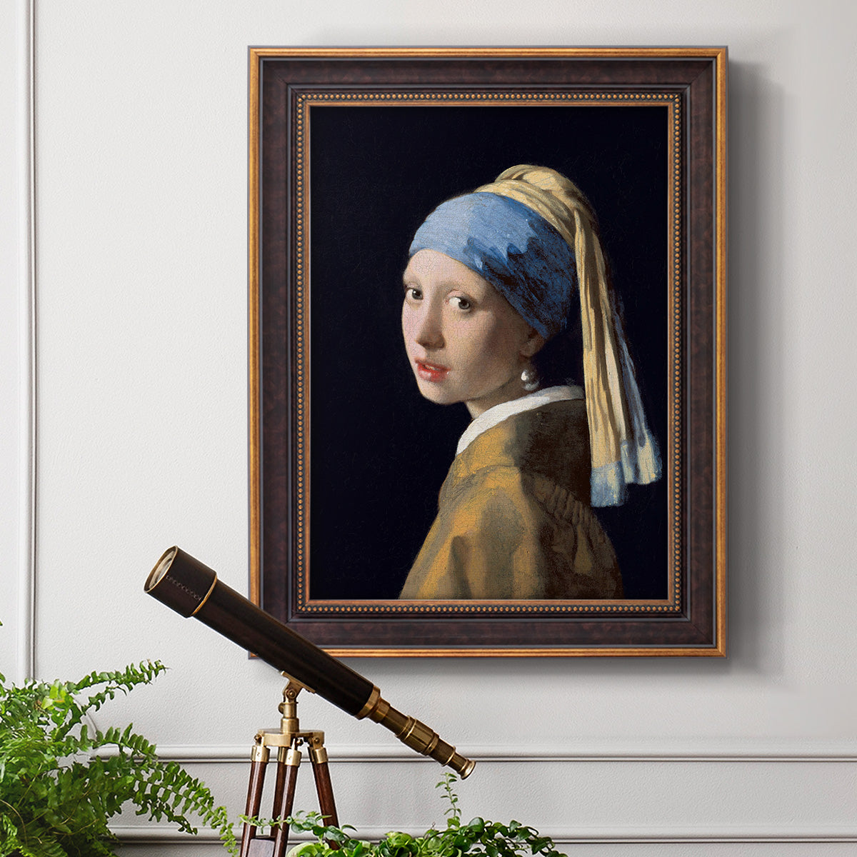 Iconic portrait of a girl wearing a pearl earring by Johannes Vermeer in an ornate bronzed mahogany wood frame displayed in a light-toned interior setting.