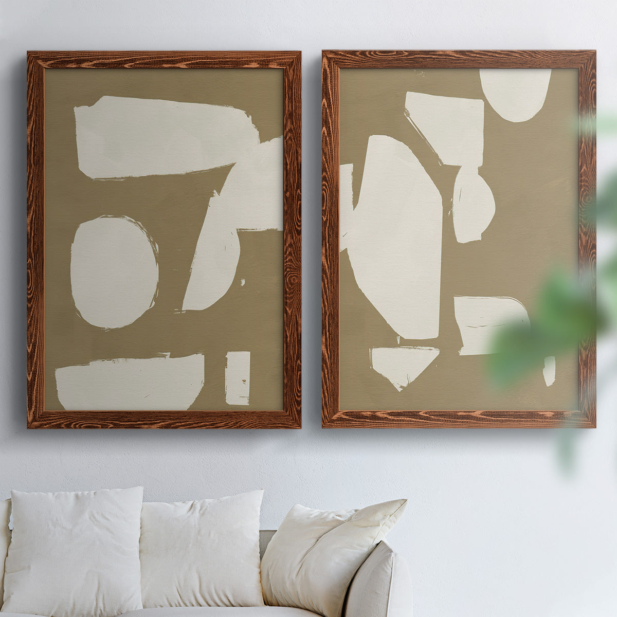 Set of two maple barnwood framed canvas prints depicting flat blocky forms, rough painted edges, and strong negative space arranged across two complementary compositions above a sofa in a bright living space.