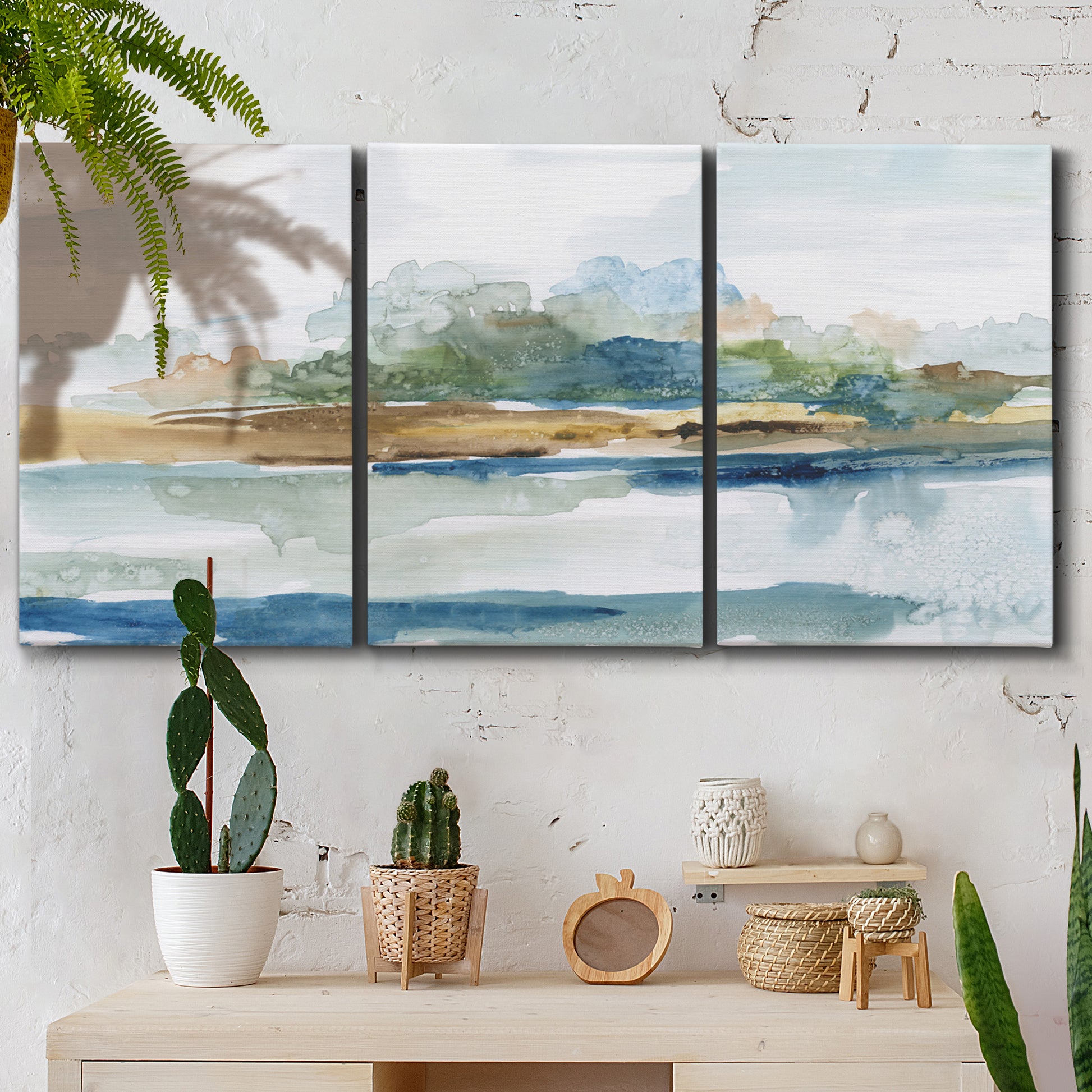 Three-panel canvas wall art featuring flowing blue abstract watercolor, displayed in a boho-chic entryway above a console table.