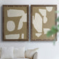 Set of two walnut barnwood framed canvas prints depicting flat blocky forms, rough painted edges, and strong negative space arranged across two complementary compositions above a sofa in a bright living space.