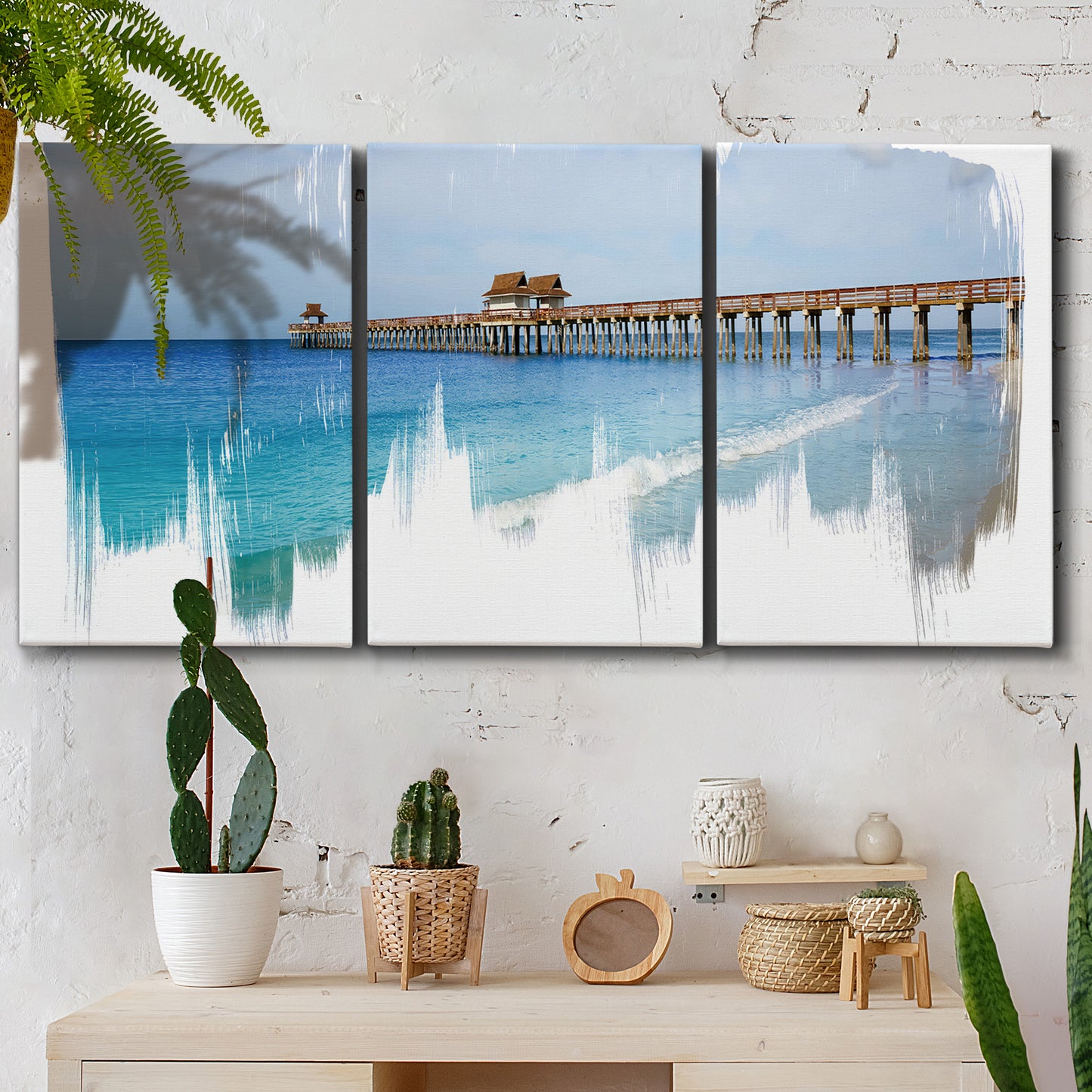 Three-panel canvas wall art featuring coastal pier extending over water, displayed in a boho-chic entryway above a console table.