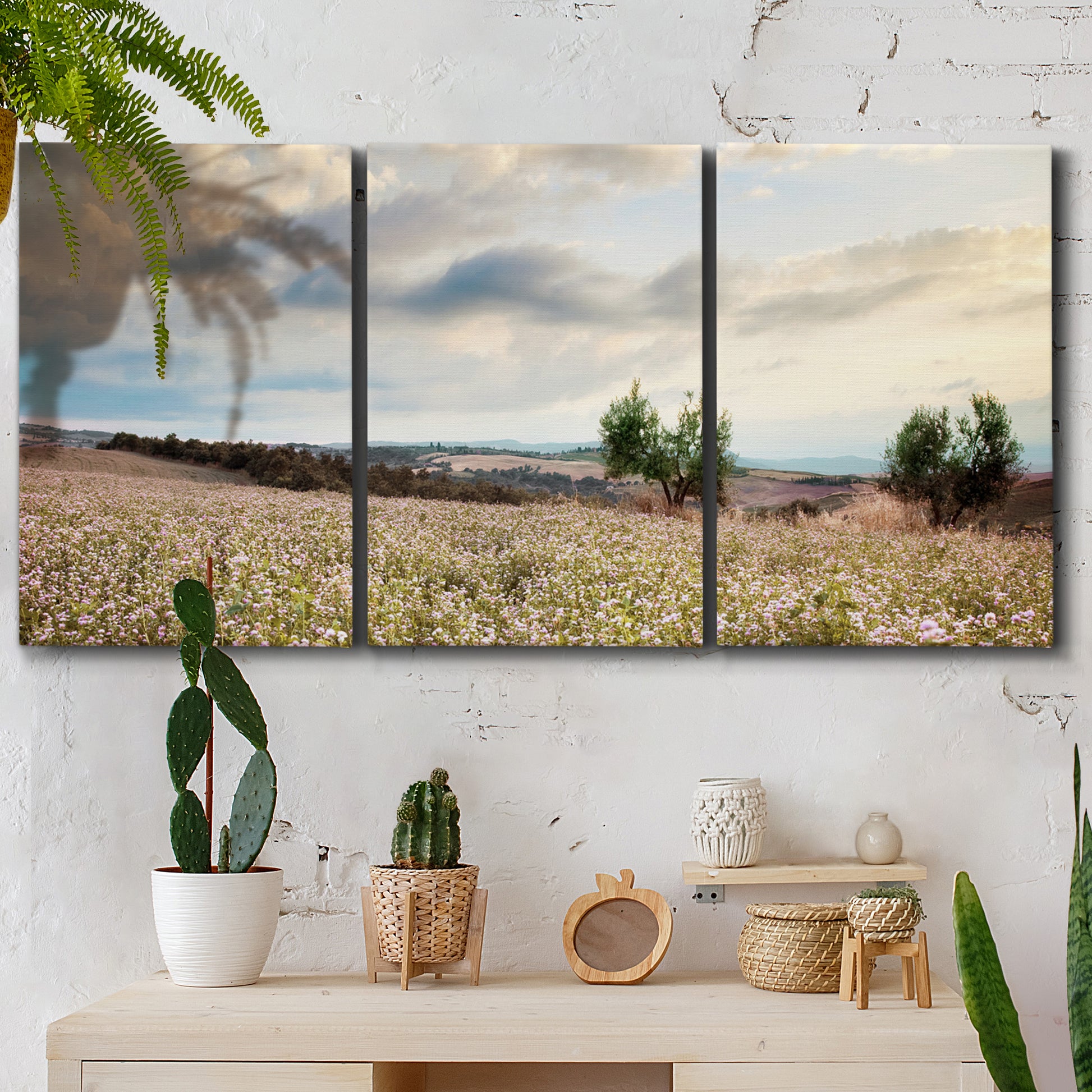 Three-panel canvas wall art featuring wildflowers across tuscan landscape, displayed in a boho-chic entryway above a console table.