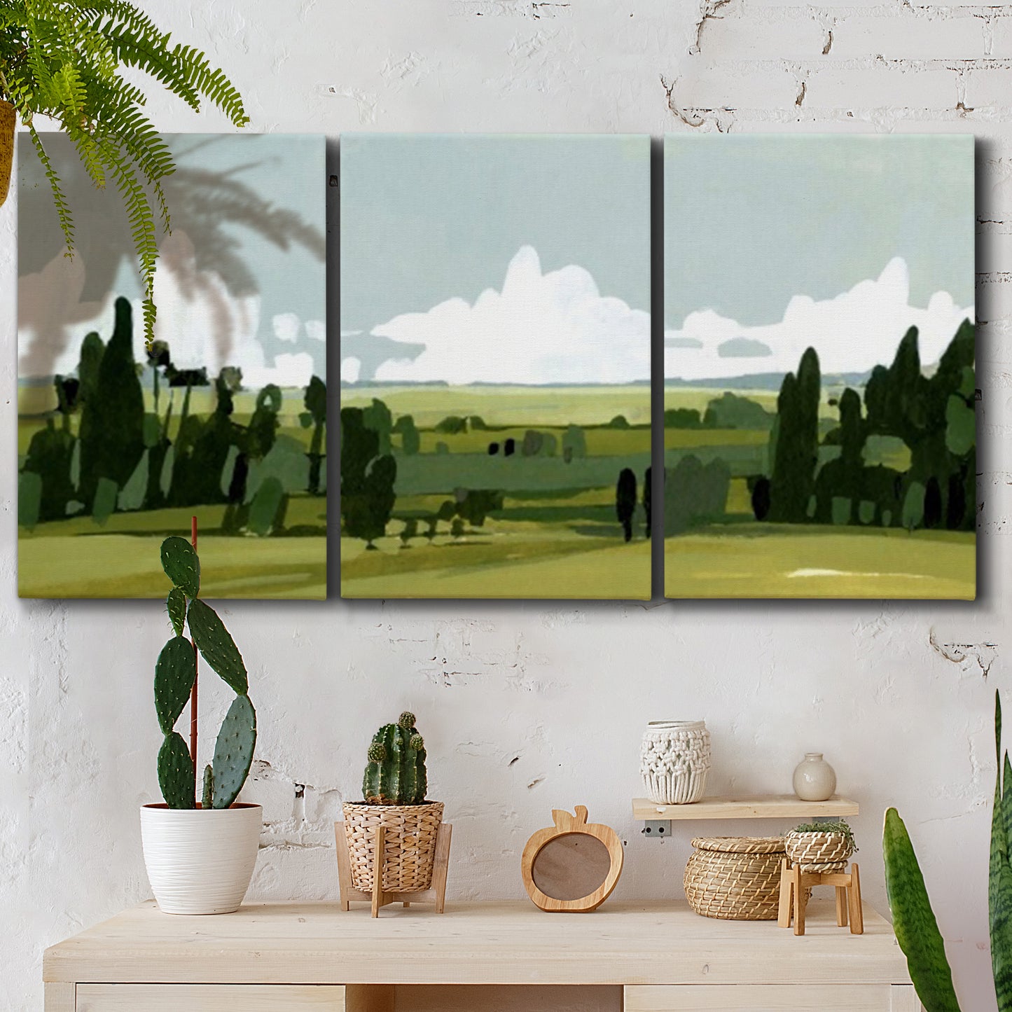 Three-panel canvas wall art featuring lush green summer countryside, displayed in a boho-chic entryway above a console table.
