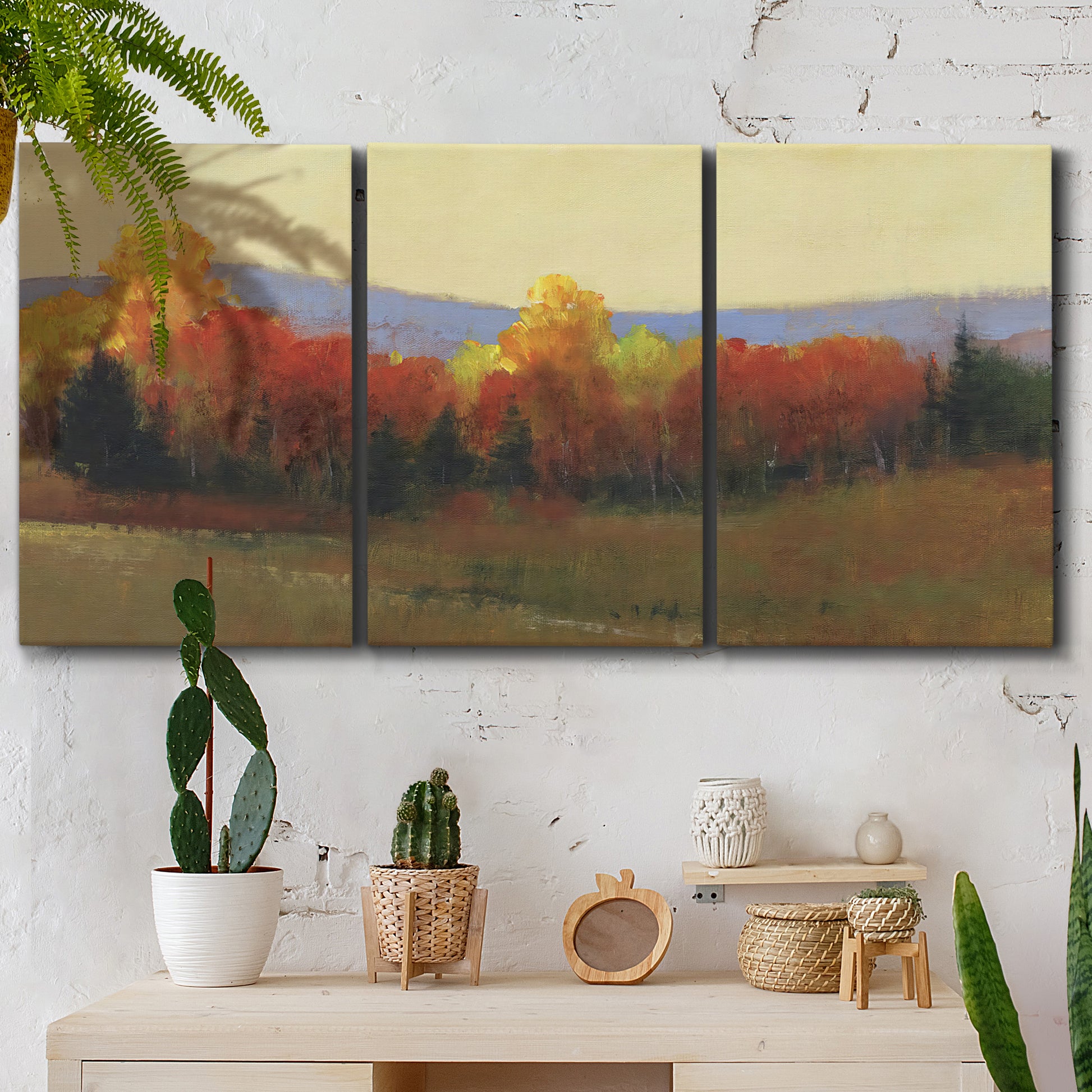 Three-panel canvas wall art featuring autumn landscape changing foliage, displayed in a boho-chic entryway above a console table.