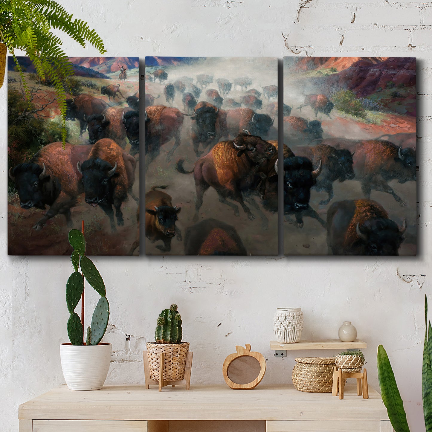Three-panel canvas wall art featuring stormy canyon landscape with animals, displayed in a boho-chic entryway above a console table.