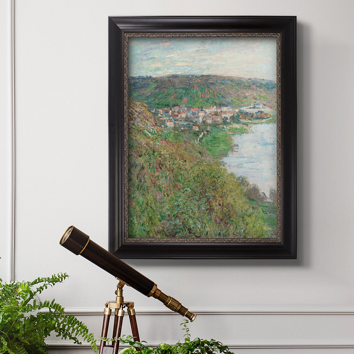 Impressionist landscape view of Vétheuil by Claude Monet in an ornate black frame with gilded inner detail displayed in a light-toned interior setting.