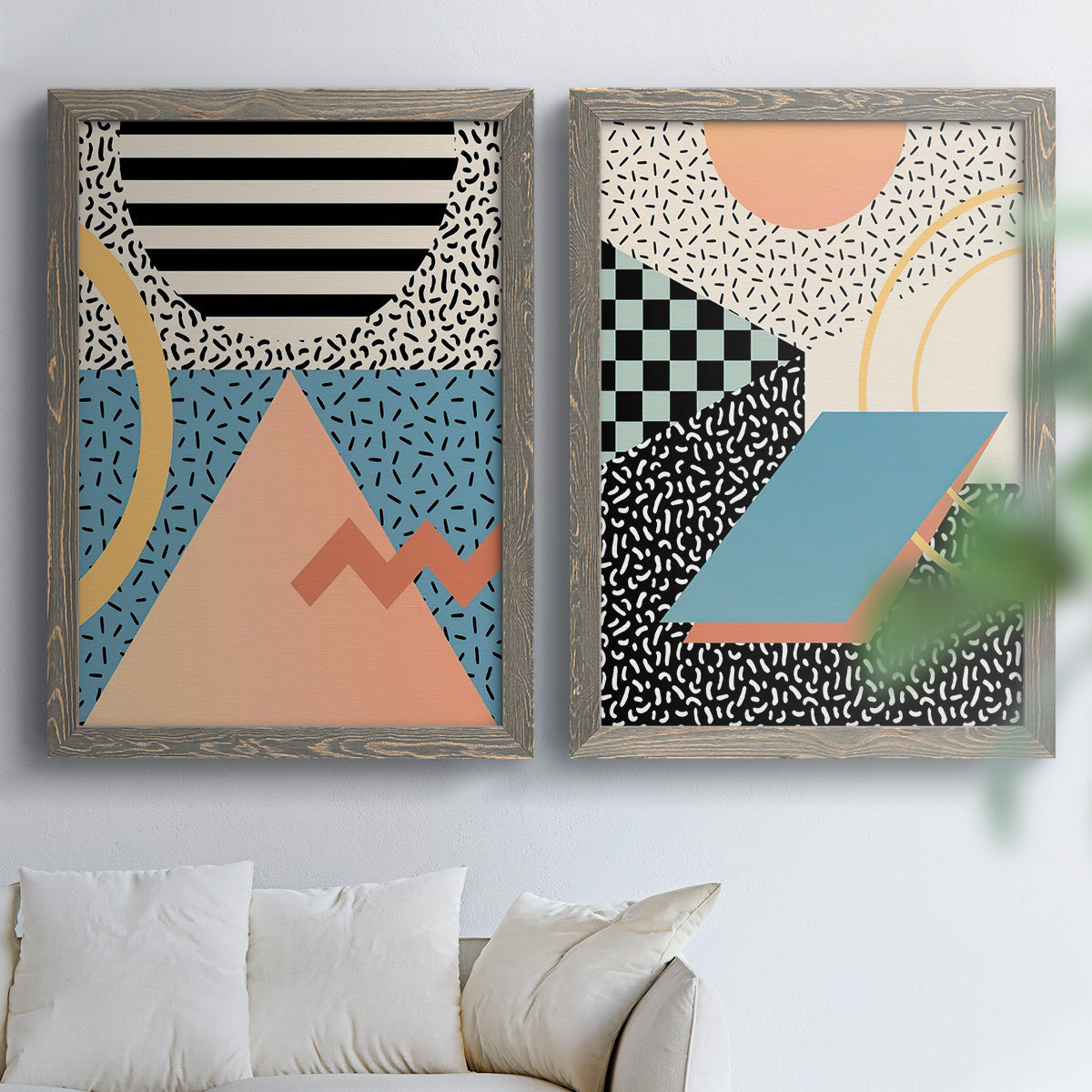 Set of two gray barnwood framed canvas prints depicting checkerboards stripes squiggles peach blue black and mint shapes arranged across two complementary compositions above a sofa in a bright living space.