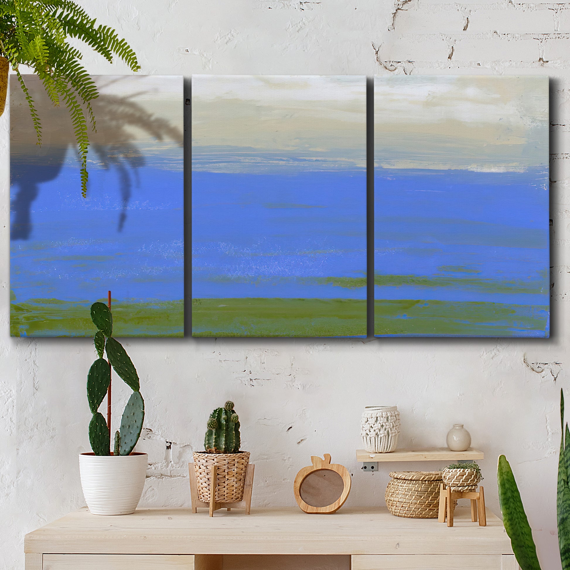Three-panel canvas wall art featuring abstract coastal inlet landscape, displayed in a boho-chic entryway above a console table.