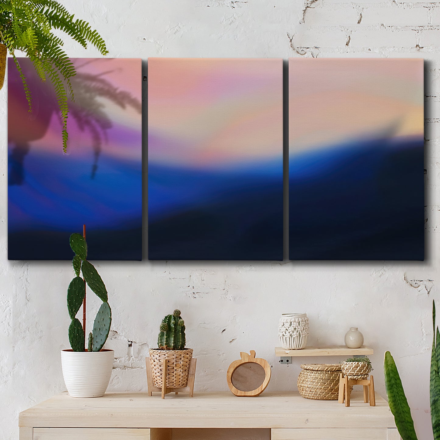 Three-panel canvas wall art featuring smooth abstract sunset color gradient, displayed in a boho-chic entryway above a console table.