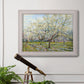 Impressionist white-blossomed orchard landscape by Vincent van Gogh in an ornate weathered white frame displayed in a light-toned interior setting.