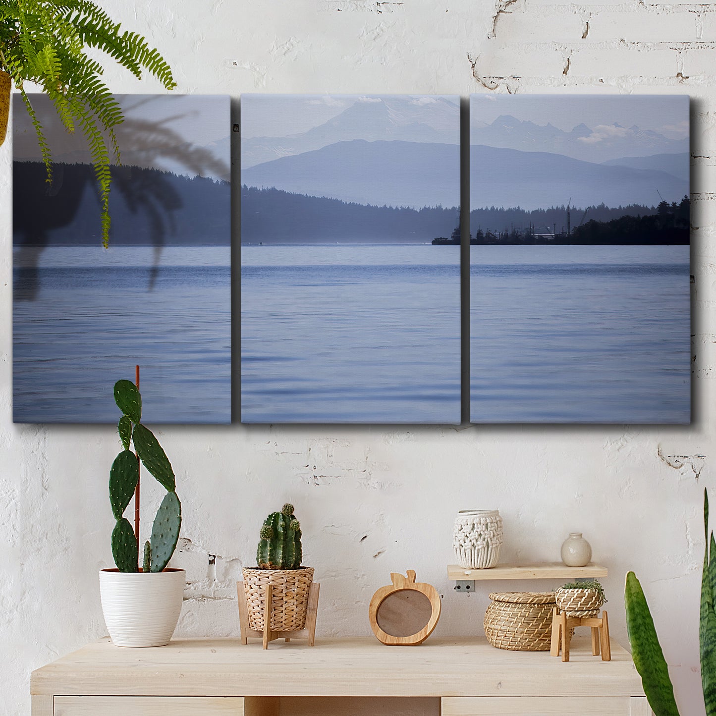 Three-panel canvas wall art featuring calm blue water landscape, displayed in a boho-chic entryway above a console table.