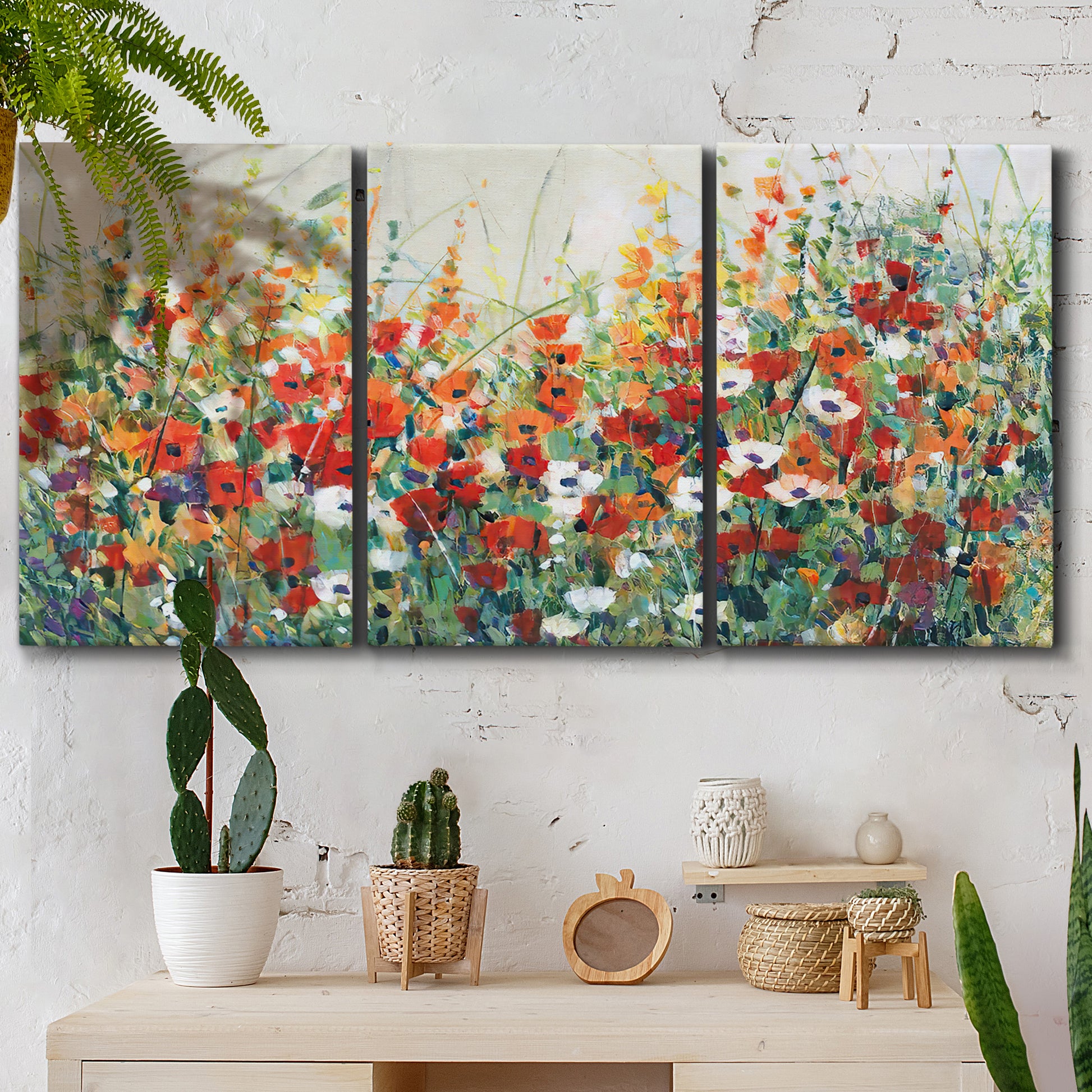 Three-panel canvas wall art featuring colorful garden flowers in bloom, displayed in a boho-chic entryway above a console table.
