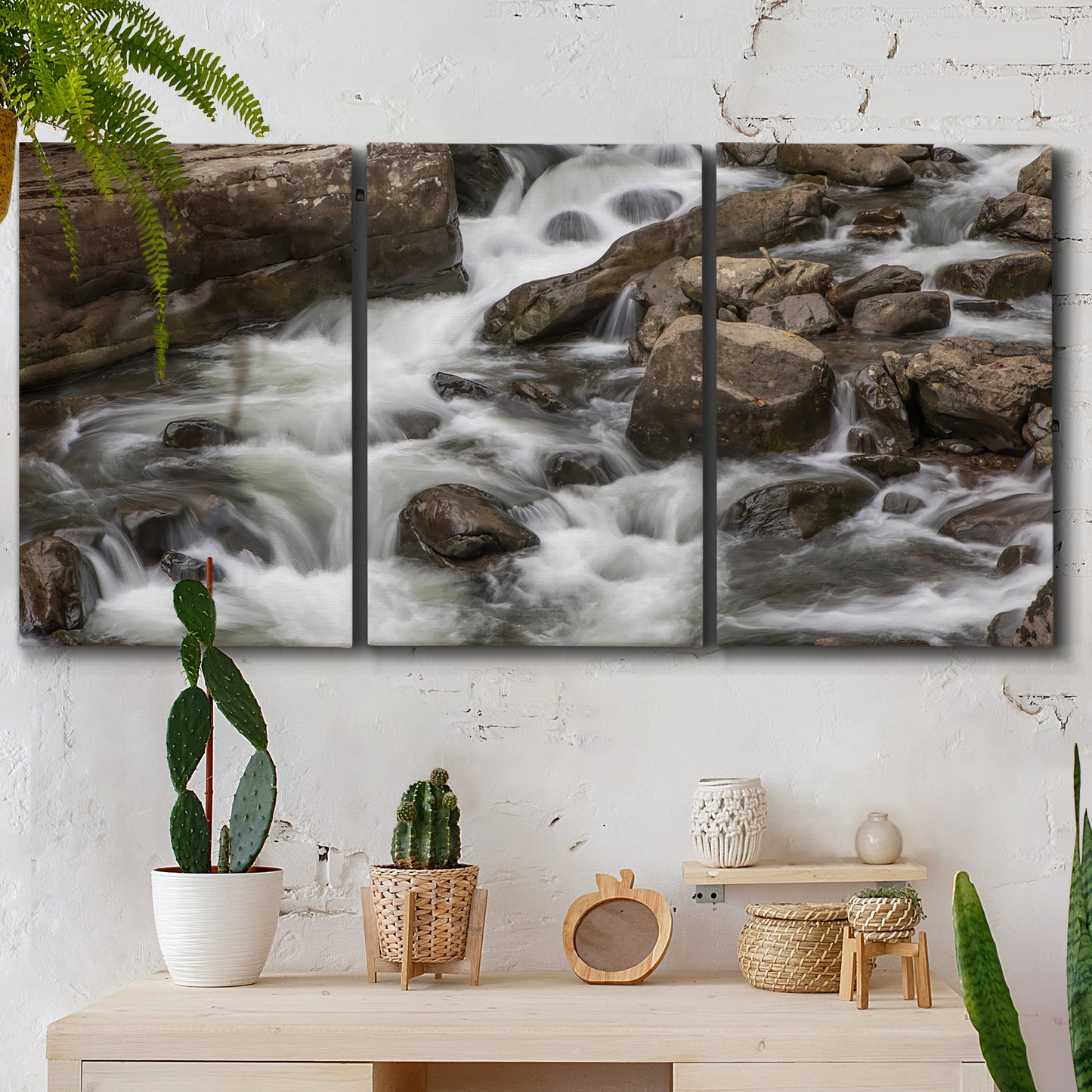 Three-panel canvas wall art featuring rushing river water over rocks, displayed in a boho-chic entryway above a console table.