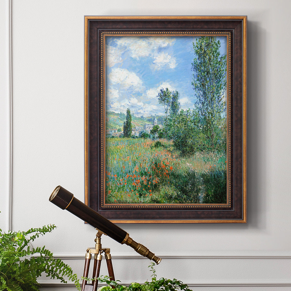 Impressionist pastoral landscape with poppy fields by Claude Monet in an ornate bronzed mahogany wood frame displayed in a light-toned interior setting.