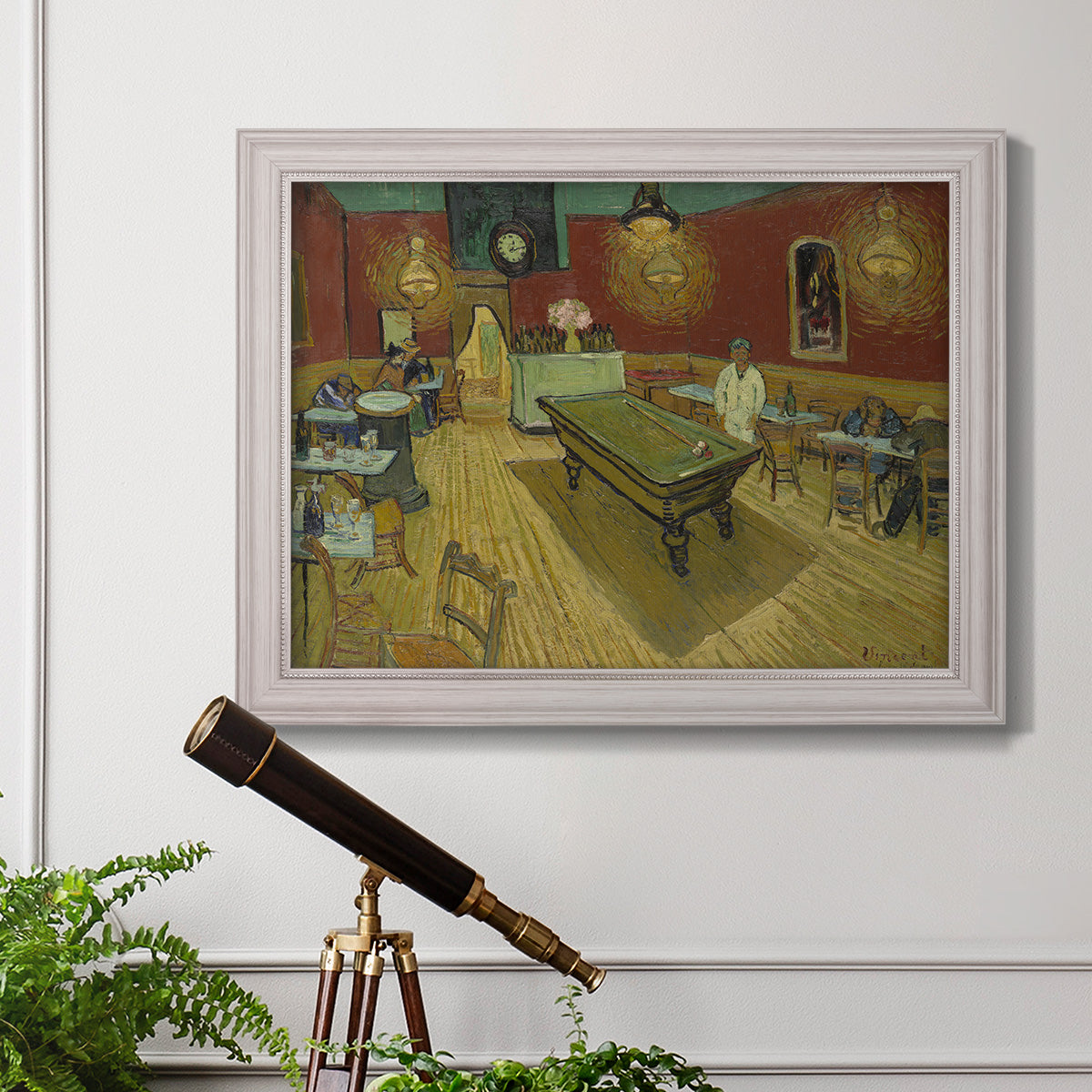 Impressionist interior of a night café by Vincent van Gogh in an ornate weathered white frame displayed in a light-toned interior setting.