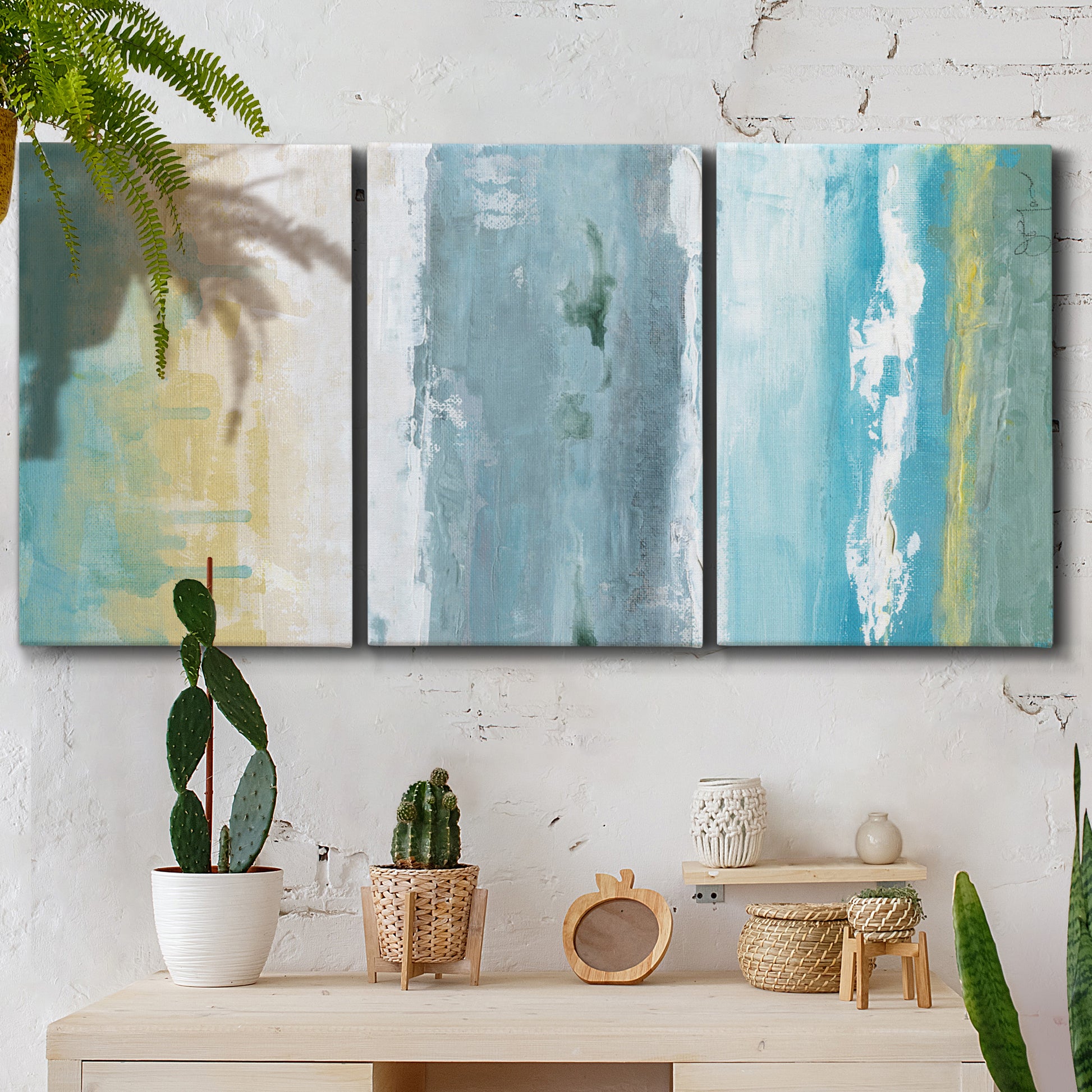 Three-panel canvas wall art featuring abstract coastal shoreline textures, displayed in a boho-chic entryway above a console table.