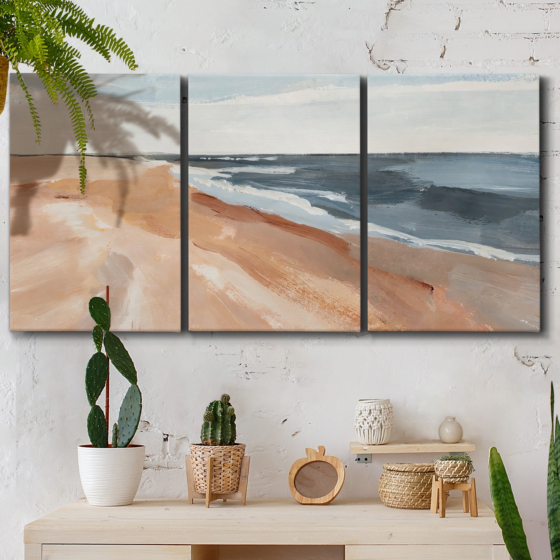 Three-panel canvas wall art featuring abstract coastal beach composition, displayed in a boho-chic entryway above a console table.