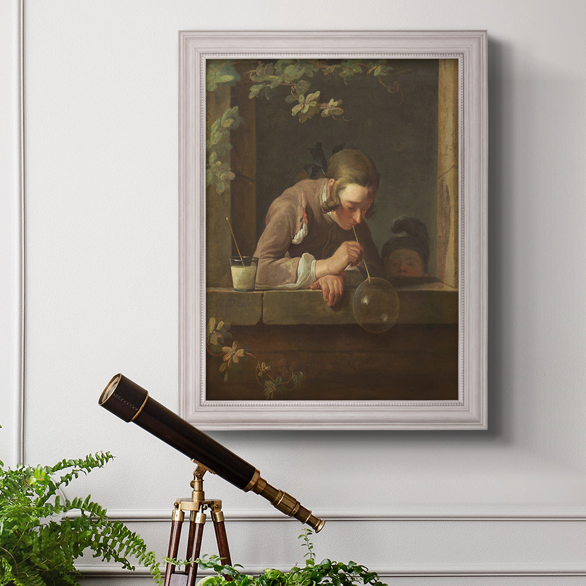 Classical genre painting of a child blowing soap bubbles by Jean-Siméon Chardin in an ornate weathered white frame displayed in a light-toned interior setting.