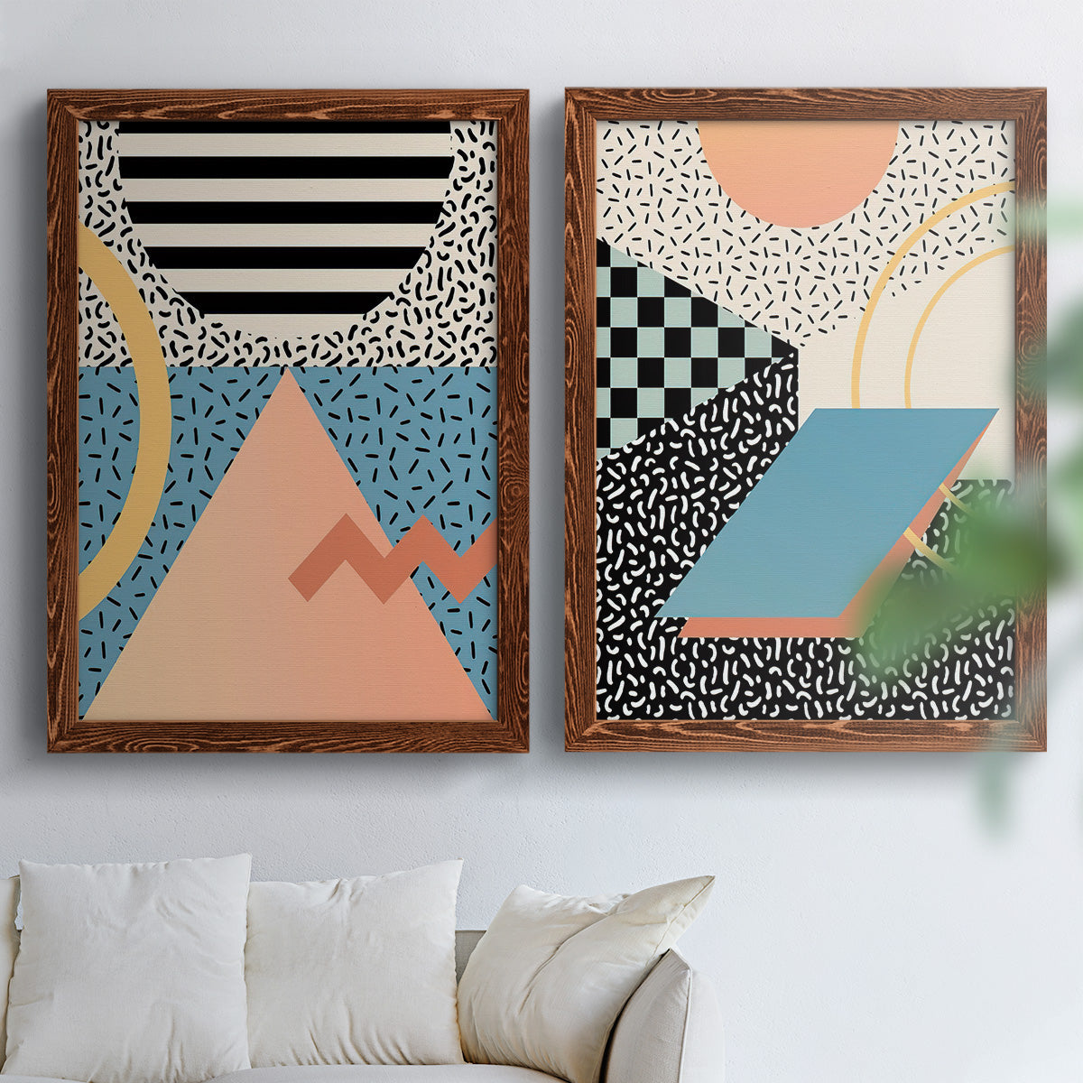 Set of two maple barnwood framed canvas prints depicting checkerboards stripes squiggles peach blue black and mint shapes arranged across two complementary compositions above a sofa in a bright living space.