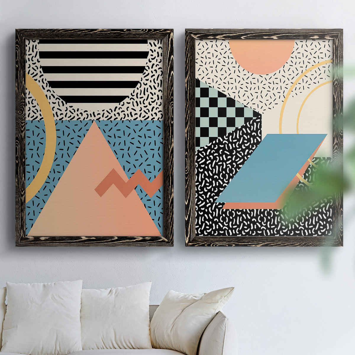 Set of two black barnwood framed canvas prints depicting checkerboards stripes squiggles peach blue black and mint shapes arranged across two complementary compositions above a sofa in a bright living space.