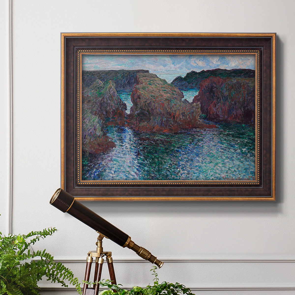 Impressionist rocky seascape by Claude Monet in an ornate bronzed mahogany wood frame displayed in a light-toned interior setting.