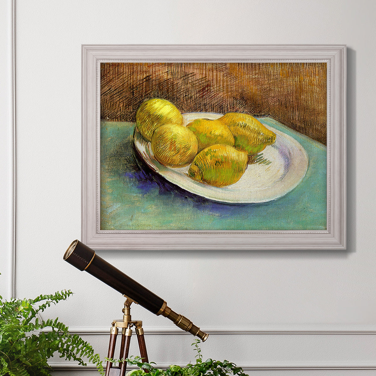 Impressionist still life with lemons by Vincent van Gogh in an ornate weathered white frame displayed in a light-toned interior setting.