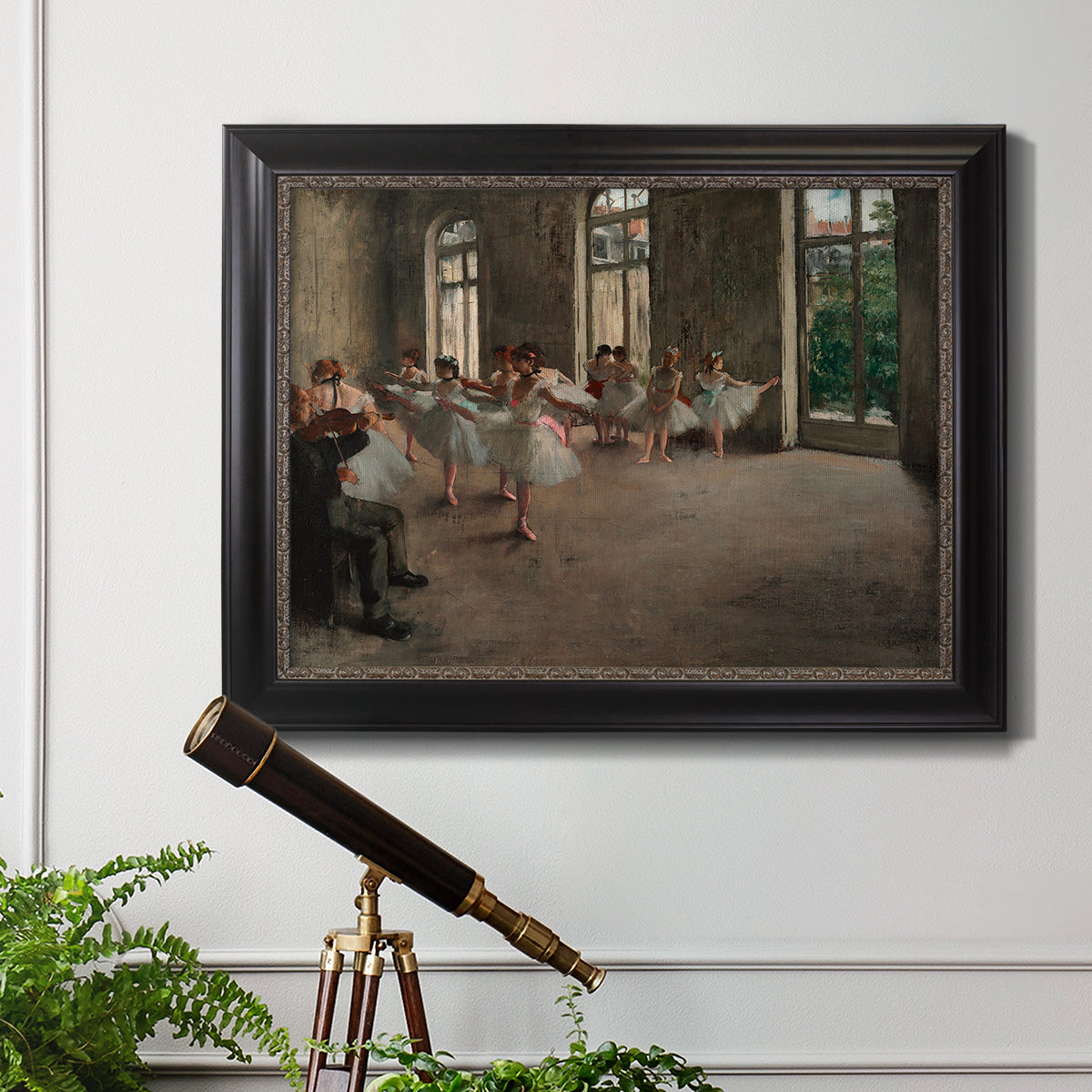 Early impressionist ballet rehearsal painting by Edgar Degas in an ornate black frame with gilded inner detail displayed in a light-toned interior setting.