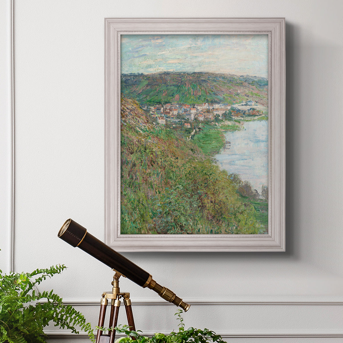 Impressionist landscape view of Vétheuil by Claude Monet in an ornate weathered white frame displayed in a light-toned interior setting.
