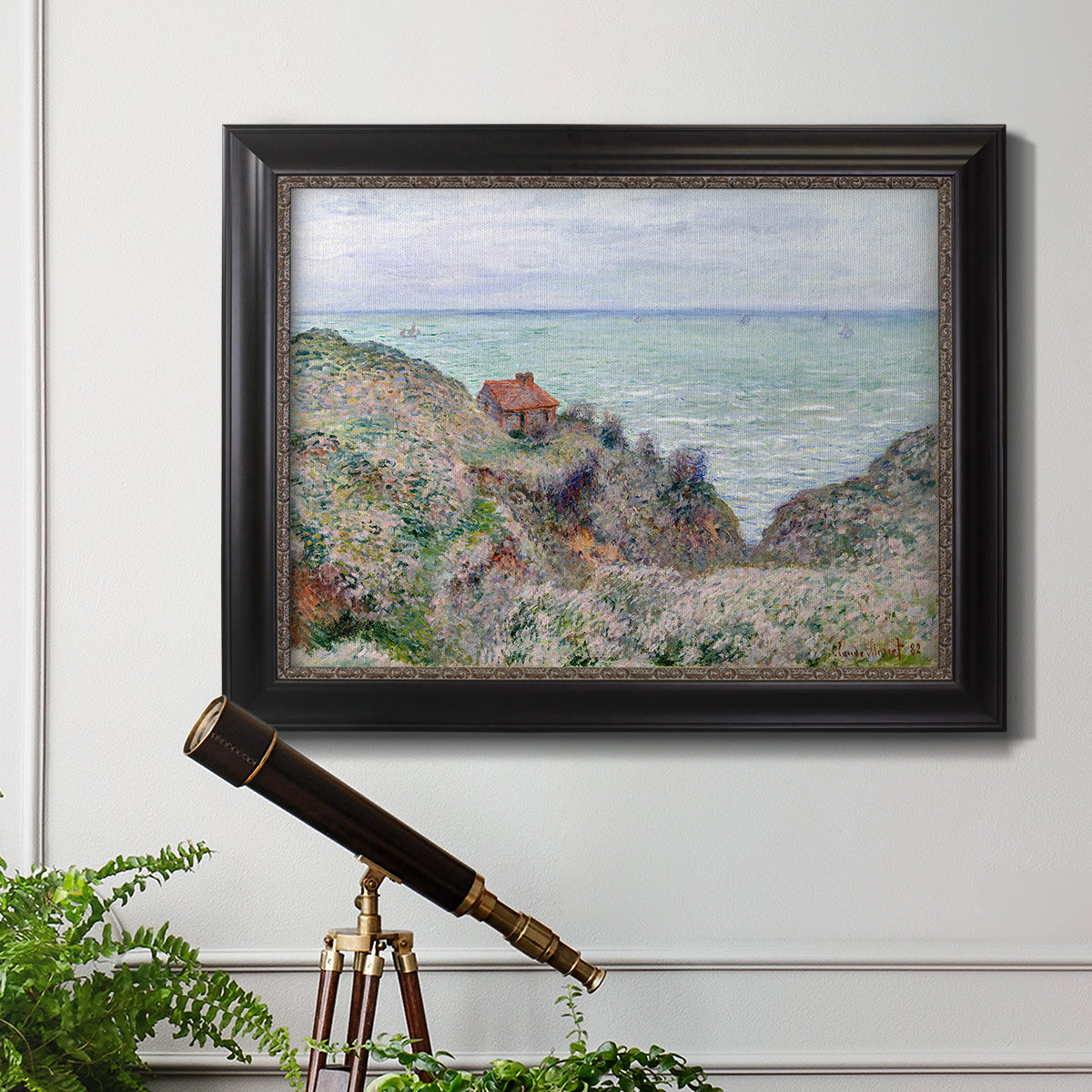 Impressionist coastal watch cabin scene by Claude Monet in an ornate black frame with gilded inner detail displayed in a light-toned interior setting.