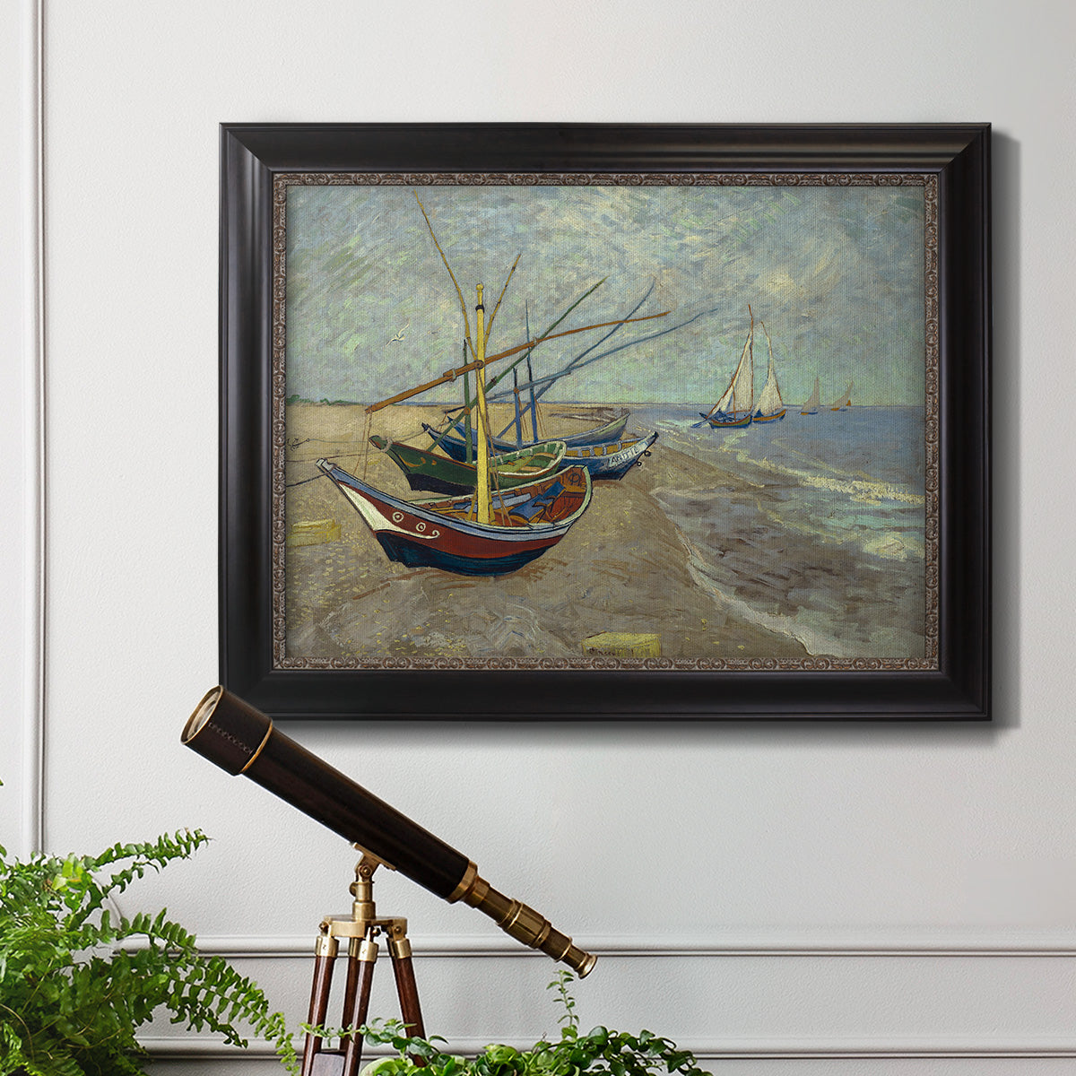 Impressionist coastal fishing boats scene by Vincent van Gogh in an ornate black frame with gilded inner detail displayed in a light-toned interior setting.