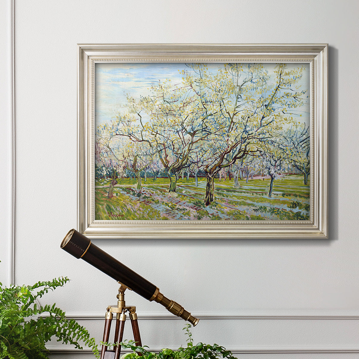 Impressionist white-blossomed orchard landscape by Vincent van Gogh in an ornate champagne frame displayed in a light-toned interior setting.