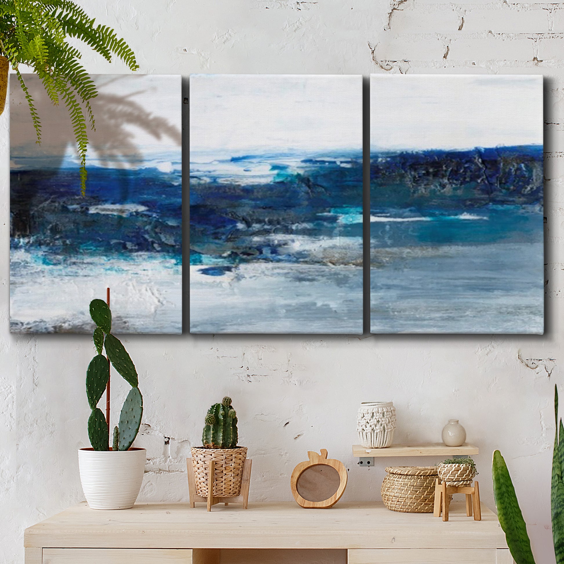 Three-panel canvas wall art featuring moody abstract sea with depth, displayed in a boho-chic entryway above a console table.