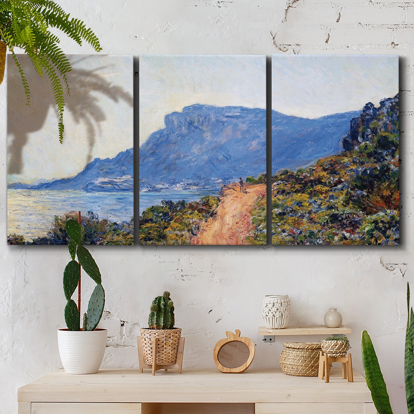 Three-panel canvas wall art featuring winding coastal road above sea, displayed in a boho-chic entryway above a console table.