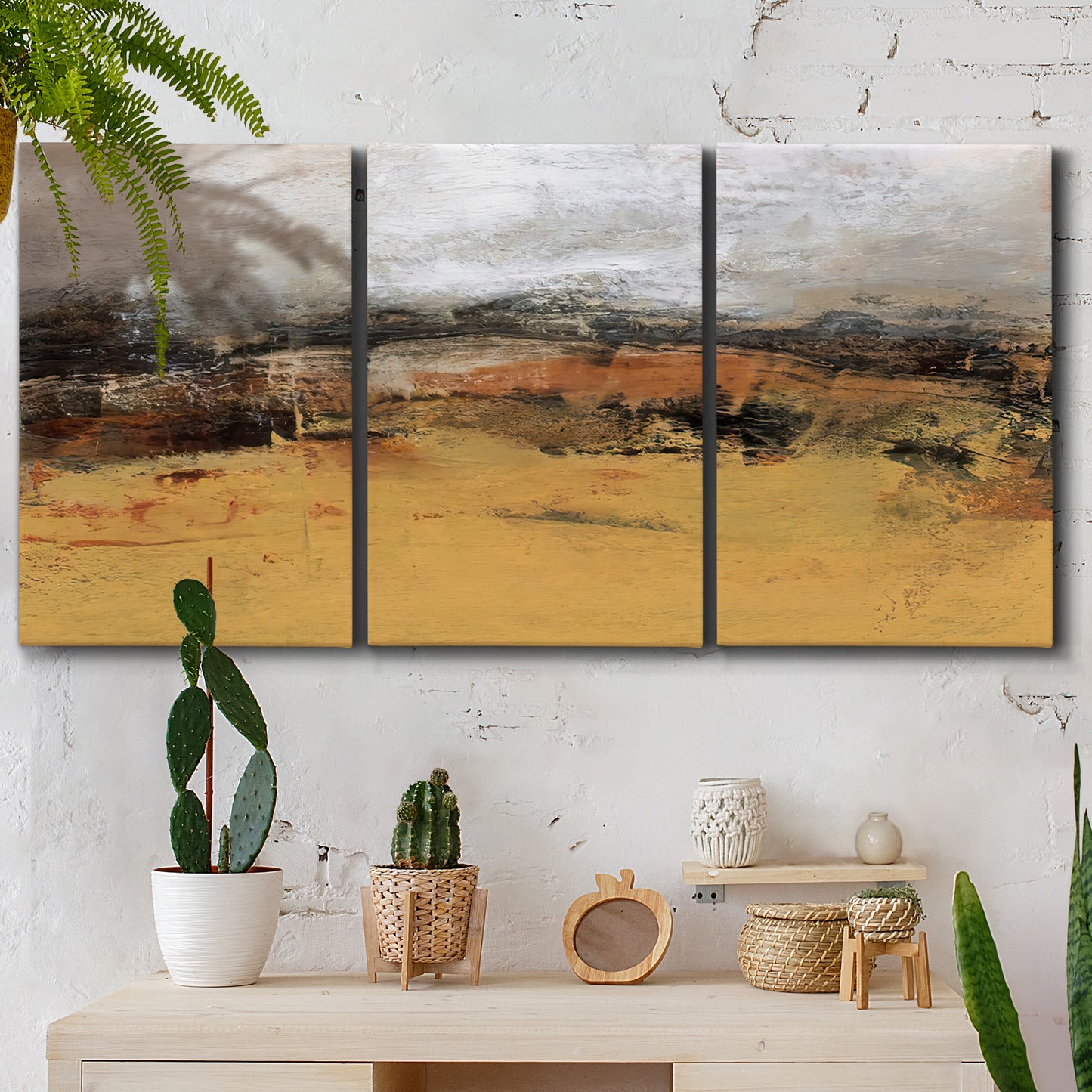 Three-panel canvas wall art featuring abstract bridge landscape in ochre, displayed in a boho-chic entryway above a console table.