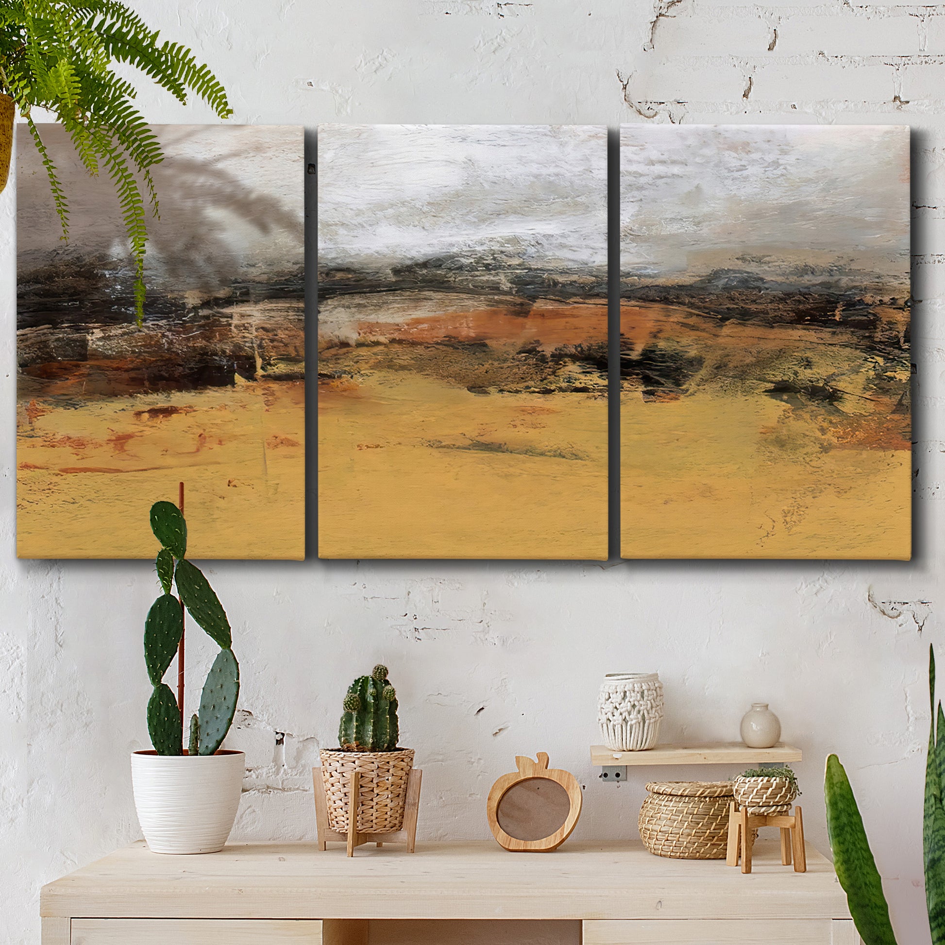 Three-panel canvas wall art featuring abstract bridge landscape in ochre, displayed in a boho-chic entryway above a console table.