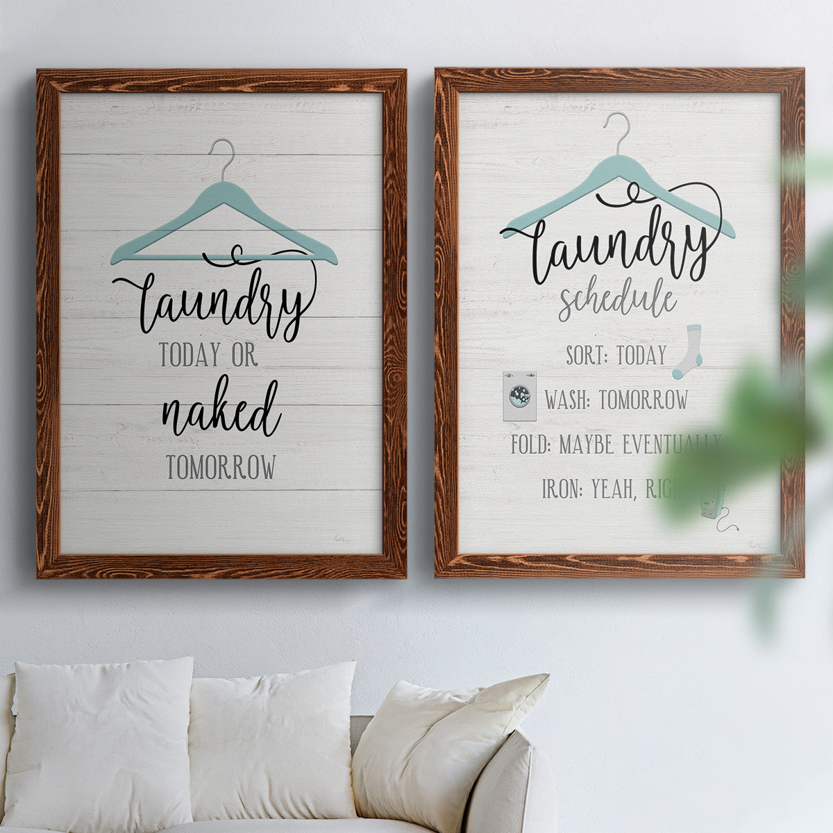 Set of two maple barnwood framed canvas prints depicting hand-lettered phrases, socks hangers and laundry symbols on linen texture arranged across two complementary compositions above a sofa in a bright living space.